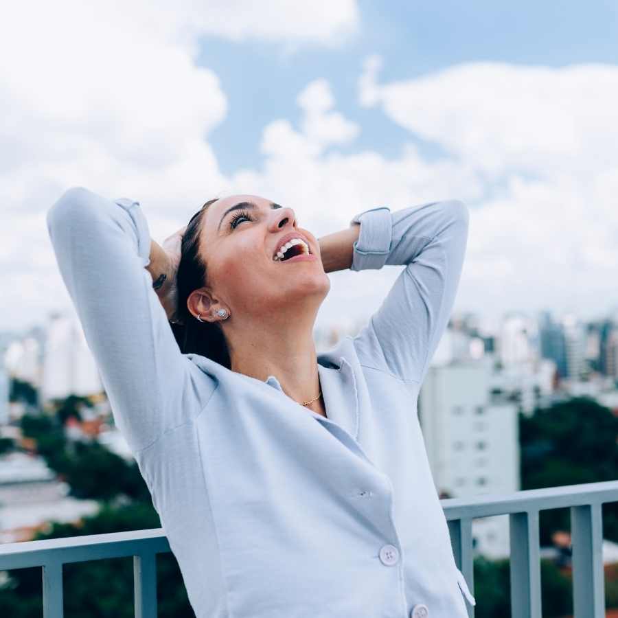 Woman looking to the sky putting her hands behind her head smiling
